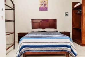 A bedroom with a wooden bed, a nightstand, a wardrobe, and a wall-mounted shelf. - Casa Madero #2, 1 block from the Malecón (La Paz)