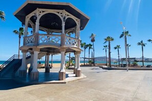 A gazebo with a balcony, located near a beach with palm trees and a clear sky. - Casa Madero #2, 1 block from the Malecón (La Paz)