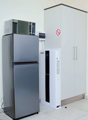 A stainless steel refrigerator and a white air conditioning unit in a room with a white cabinet and a no-smoking sign. - Royal Golfview Stay  - Welcoming luxury 1-bedroom Apartment near OR Tambo (Boksburg)