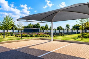 A covered outdoor seating area with a paved floor, surrounded by a low fence and a variety of plants and flowers. - Royal Golfview Stay  - Welcoming luxury 1-bedroom Apartment near OR Tambo (Boksburg)