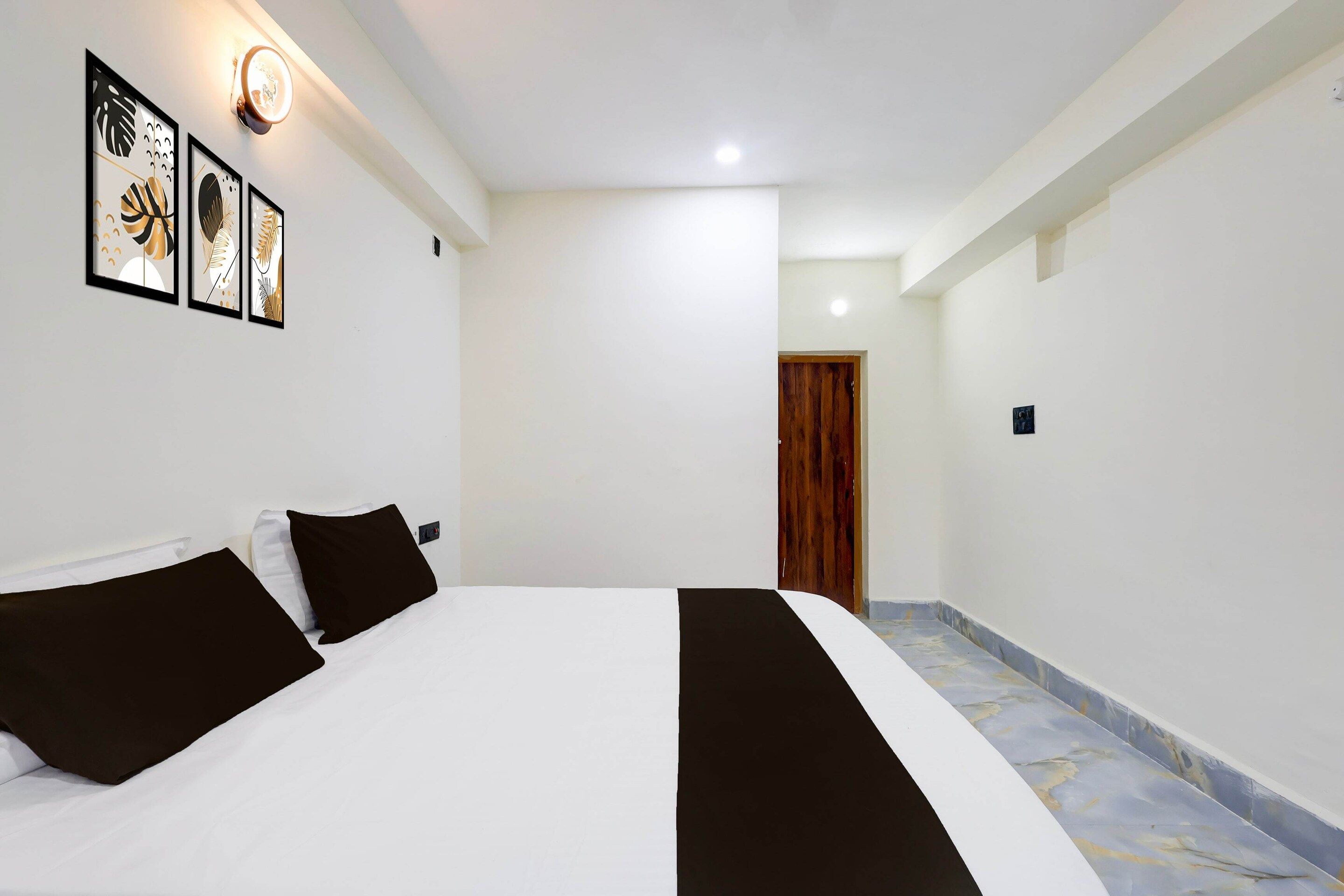 Une chambre d’hôtel avec un lit, une porte en bois et des œuvres d’art encadrées accrochées au mur.