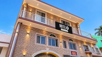 A multi-story hotel with a stone facade, balconies, and a sign indicating it is serviced by OYO.