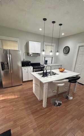 A modern kitchen with a central island, stainless steel appliances, and pendant lighting. - Cozy 2-bedroom bungalow near Mercer in Macon with AC (Macon)