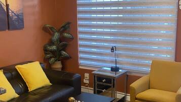 Ein Wohnzimmer mit einer Couch, einem Sessel, einem Couchtisch und einer Zimmerpflanze.