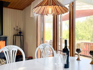 A dining area with a table, chairs, a wine bottle, and a decorative light fixture. - 7 Person Holiday Home in Graddo (Gräddö)
