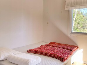 A small, single-bed room with a window, white walls, and a neatly made bed with a red patterned blanket. - 7 Person Holiday Home in Graddo (Gräddö)