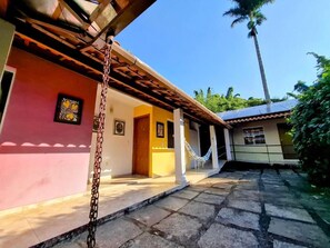 A building with a pink facade, a wooden porch, and a hammock.