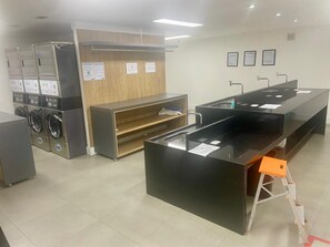 A reception area with a counter, a wooden cabinet, and a washing machine. - Habitarte | 2 suites with views and leisure facilities high up (São Paulo)