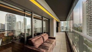 A modern interior with a sofa, large windows, and a city view. - Habitarte | 2 suites with views and leisure facilities high up (São Paulo)