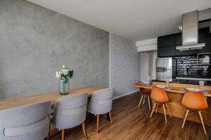 A modern kitchen with a brick accent wall, wooden dining table, and chairs. - Habitarte | 2 suites with views and leisure facilities high up (São Paulo)