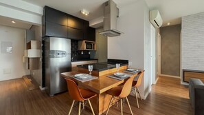 A modern kitchen with a built-in refrigerator, microwave, and stove. There is a dining table with four chairs and a glass of water on it. - Habitarte | 2 suites with views and leisure facilities high up (São Paulo)
