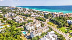 A coastal residential area with multiple-story buildings, roads, and a clear view of the ocean. - Triple Sea - 4BR Blue Mountain Beach Retreat with Rooftop Terrace (Santa Rosa Beach)