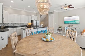 A modern kitchen with white cabinets, a wooden dining table, and a ceiling fan. - Triple Sea - 4BR Blue Mountain Beach Retreat with Rooftop Terrace (Santa Rosa Beach)
