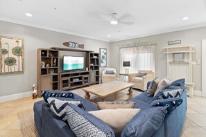 Een woonkamer met een televisie, een bank, een salontafel en een open haard.