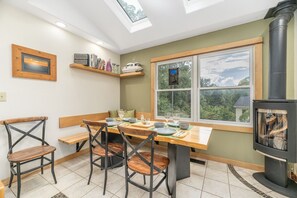 A dining area with a table set for four, a bench, and a fireplace. - House on the Hill near Blue Ridge Pkwy & Downtown (Asheville)