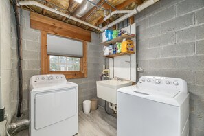 A laundry room with two washing machines, a sink, and a window. - House on the Hill near Blue Ridge Pkwy & Downtown (Asheville)