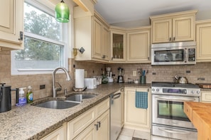 A kitchen with granite countertops, stainless steel appliances, and beige cabinetry. - House on the Hill near Blue Ridge Pkwy & Downtown (Asheville)