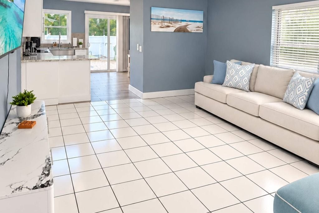 A modern living room with a sofa, a television, and a kitchen area in the background.