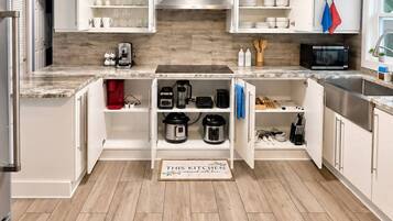 A modern kitchen with white cabinets, a granite countertop, and a built-in stove.