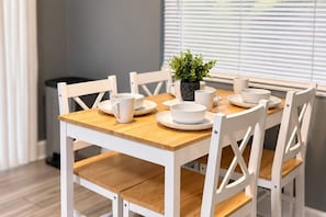 A dining table with white chairs, white plates, and a small potted plant.