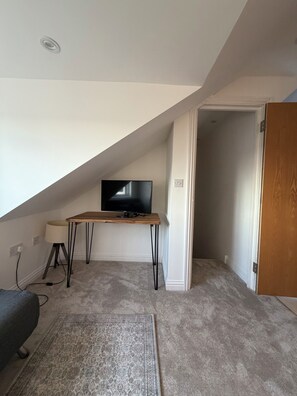 A room with a television on a wooden stand, a lamp, and a patterned rug. - Stylish 2 bedroom apartment, just 15 minutes walk from Uxbridge town centre. (Uxbridge)