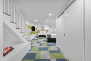 A modern interior with a staircase, a bed, a television, and a patterned carpet. - Modern Palm Springs Retreat| 4 BR 4 Bath| Central (Pittsburgh)