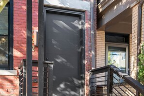 A modern building with a closed garage door, a metal staircase, and a brick facade. - Modern Palm Springs Retreat| 4 BR 4 Bath| Central (Pittsburgh)