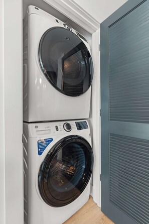 A stacked washer and dryer unit with a control panel and a label indicating 'SMARTER LAUNDRY' features. - The Rhiannon | Pool, Parking & Private Balcony (Nashville)