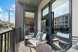 A balcony with a view of a residential area, a sofa, and a chair. - The Rhiannon | Pool, Parking & Private Balcony (Nashville)