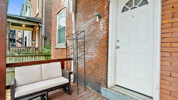 A brick exterior with a white door, a wooden bench, and a metal gate.