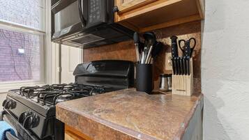 A kitchen with a gas stove, a microwave, and a knife block on the countertop.