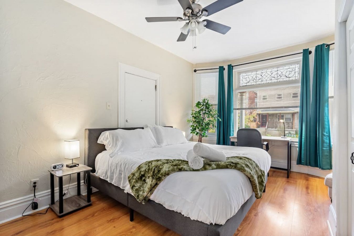 A bedroom with a bed, bedside table, lamp, and a ceiling fan.
