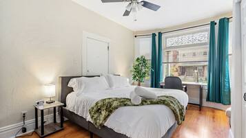 A bedroom with a bed, bedside table, lamp, and a ceiling fan.