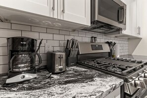 Eine Küche mit Kaffeemaschine, Toaster, Messern und einem Herd.