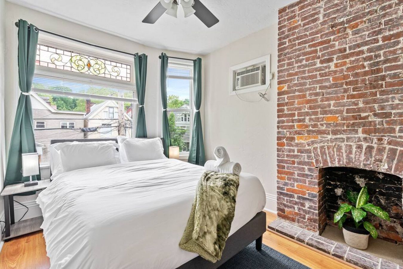 A hotel room with a bed, a brick fireplace, and a view of the outside.