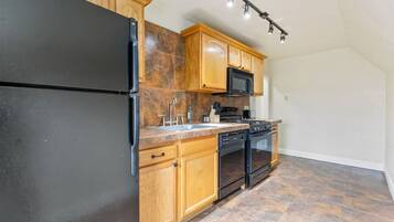 A kitchen with wooden cabinets, a black refrigerator, a microwave, a stove, and a dishwasher.