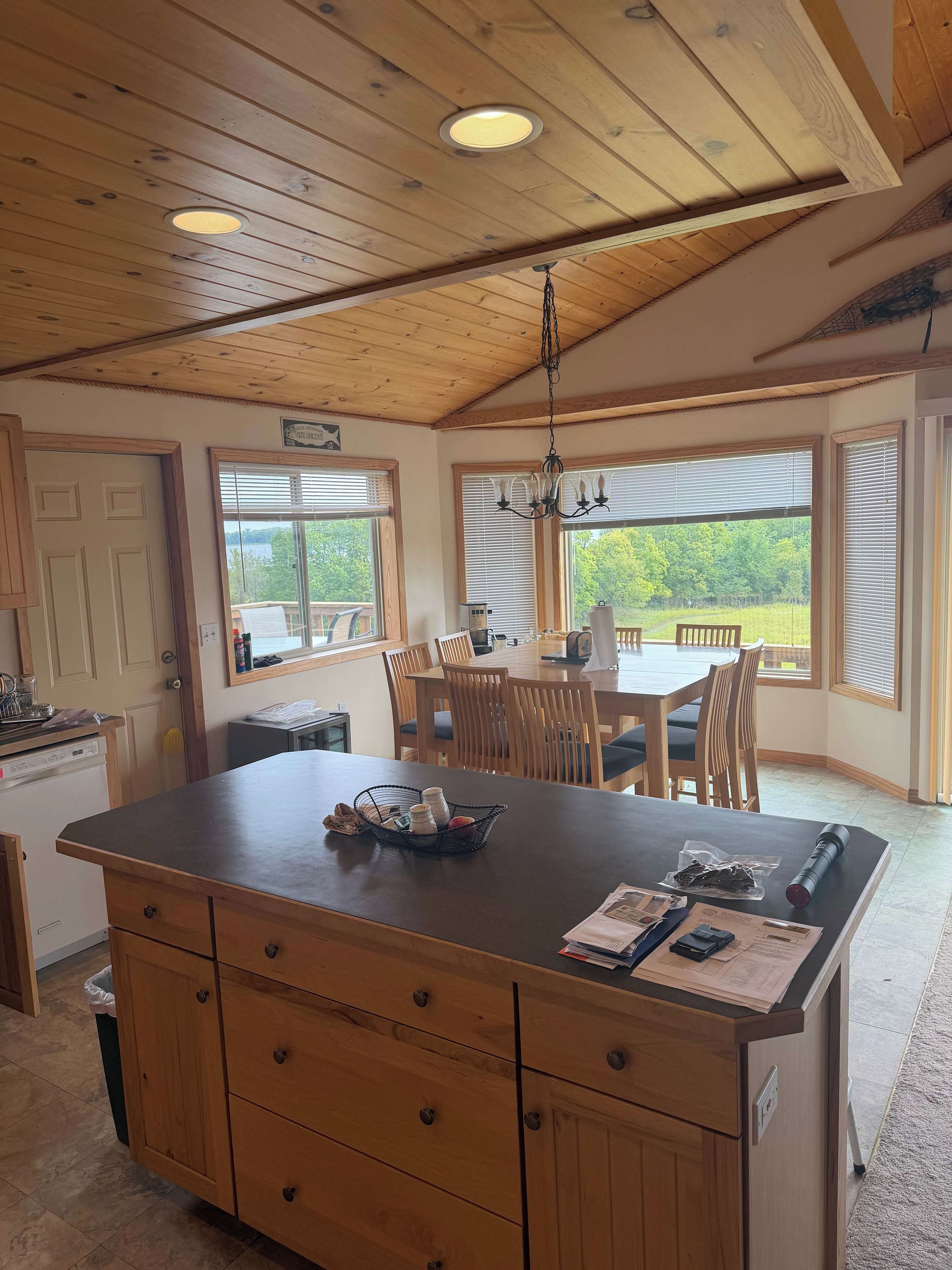 Een keuken met een houten eiland, een eettafel, stoelen en een kroonluchter.