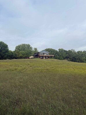 A two-story building with a balcony on the upper floor, surrounded by a grassy field and trees. - Star Lake Escape, Dent MN (Dent)