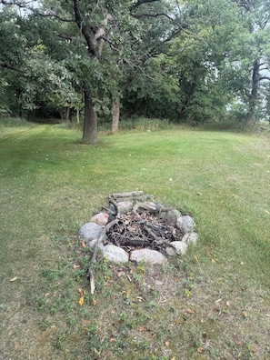 A grassy area with a fire pit surrounded by rocks and logs. - Star Lake Escape, Dent MN (Dent)