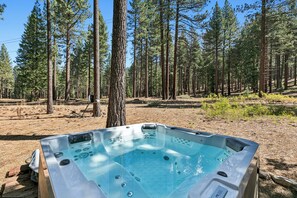 Ein Whirlpool in bewaldeter Landschaft mit hohen Bäumen und blauem Himmel.