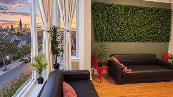 Un moderno salón con vista a la ciudad, una pared verde y un sofá de cuero negro.