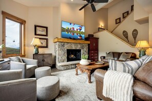 Ein Wohnzimmer mit Kamin aus Stein, einem darüber montierten Fernseher und einem Sofa mit einer Decke.