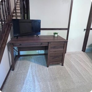 A wooden desk with a television, drawers, and a small plant. - Falcon Forest Retreat: Near Offutt AFB & Omaha Zoo (Bellevue)