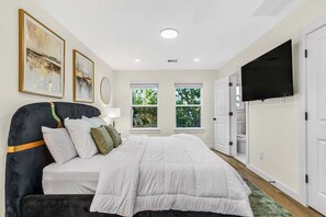 Ein Schlafzimmer mit einem Bett, einem Fernseher und Kunstwerken an der Wand.