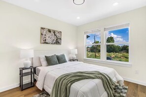 Una camera da letto con un letto, due lampade da comodino, un tavolino, un quadro e una finestra con vista.