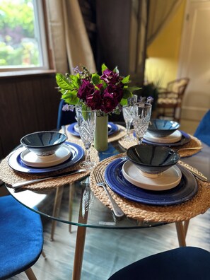 Ein Tisch ist gedeckt mit blauen und weißen Tellern, klarem Glas und einer Vase mit Blumen.