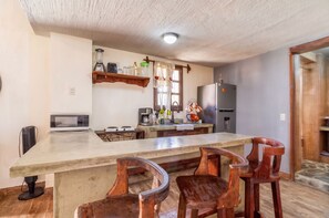 A kitchen with a central island, wooden chairs, a refrigerator, and a microwave. - Villa Isabela +10 Guests | Pool | Huge Garden (San Miguel Cuyutlán)