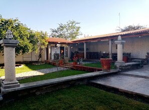 A courtyard with a tiled roof, a stone pathway, and a grassy area. - Villa Isabela +10 Guests | Pool | Huge Garden (San Miguel Cuyutlán)