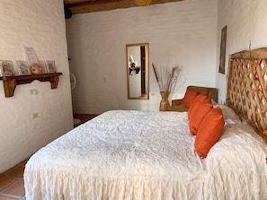 Ein Schlafzimmer mit einem großen Bett, einem Holz-Kopfteil, einem Spiegel und einem an der Wand befestigten Regal mit Dekoration.