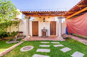 A patio with a pergola, a stone fireplace, and a tiled walkway leading to a wooden door. - Villa Isabela +10 Guests | Pool | Huge Garden (San Miguel Cuyutlán)